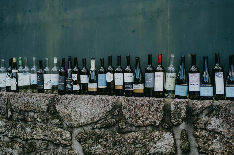 Row of wine bottles displayed on a rustic stone wall in Alsace