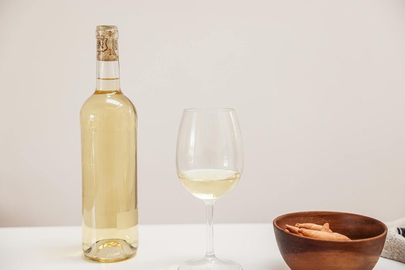 Bottle and glass of white Riesling wine on a marble surface
