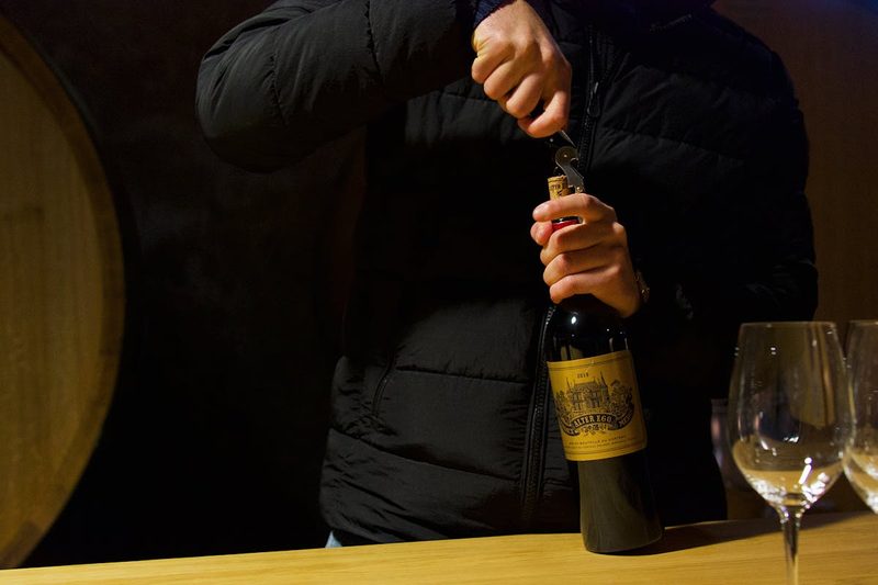 Person uncorking wine bottle during a tasting session in Margaux, Bordeaux, France
