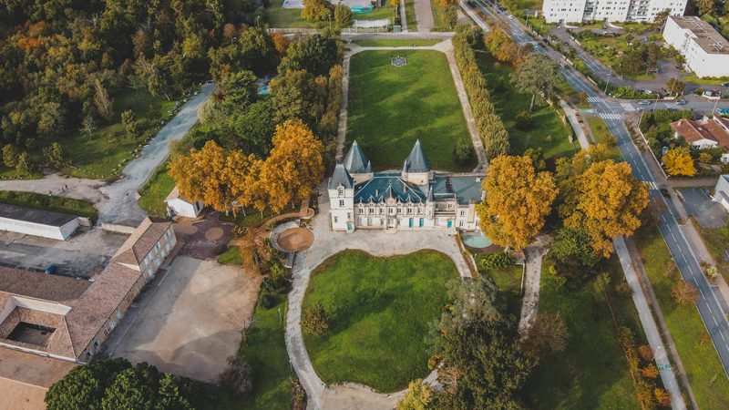 Stunning aerial view of a grand Bordeaux chateau surrounded by lush autumn foliage