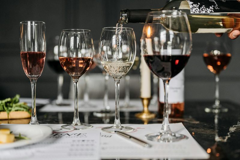 Wine tasting session with various wines being poured into glasses at a tasting event