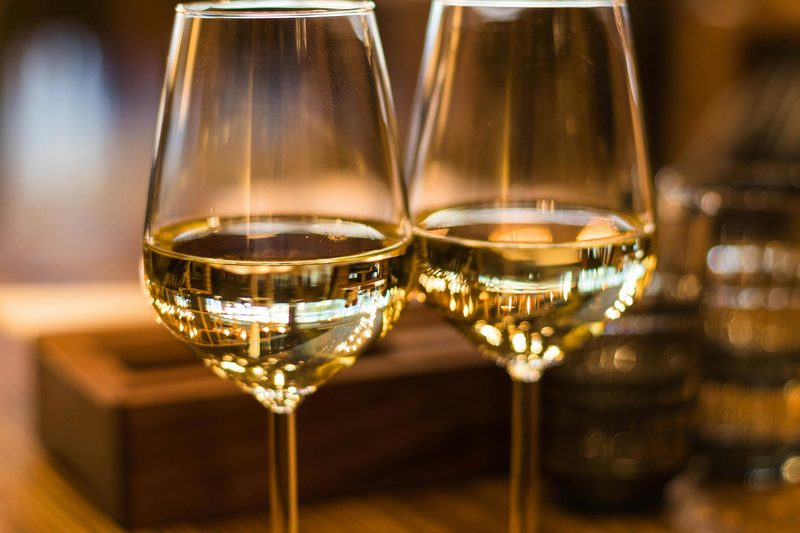 Two glasses of white wine elegantly lit, representing blanc de blancs champagne styles