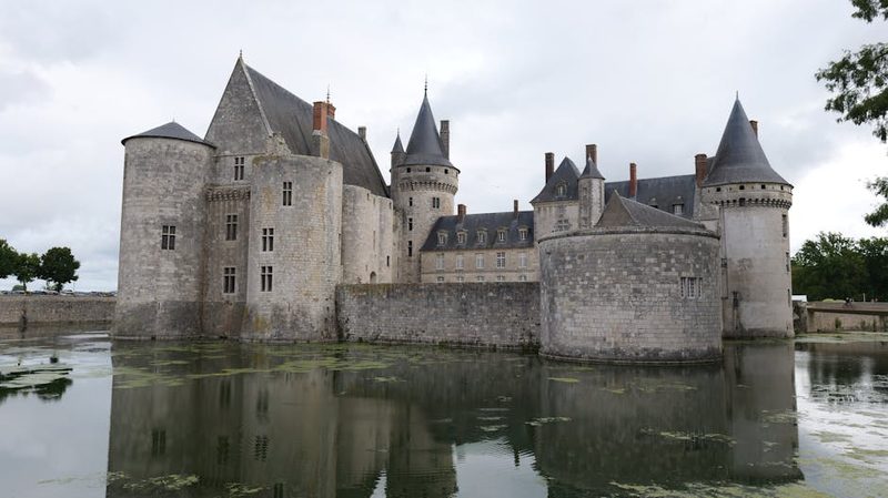 Chateau de Sully-sur-Loire reflected in water on an overcast day