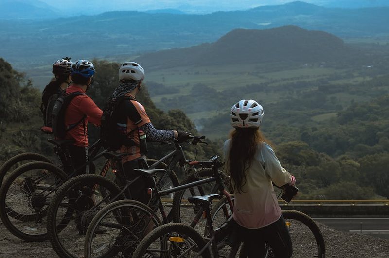 Cyclists standing on a hilltop enjoying a scenic landscape view