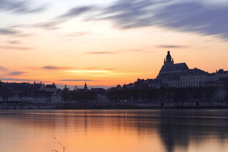 Sunset over Blois with Loire River reflection and historic buildings