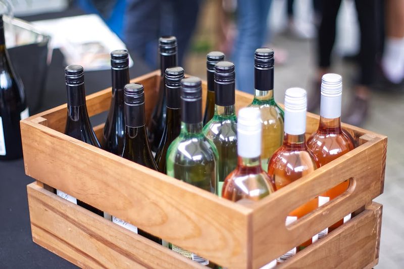 Wooden crate filled with diverse wine bottles at an outdoor market