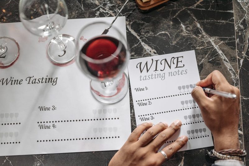 Close-up of wine tasting session with notes glasses and materials on table