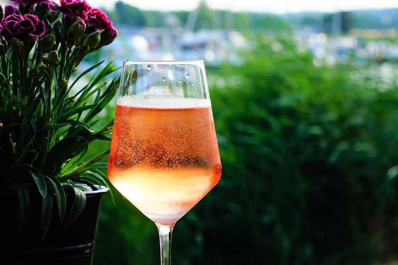 Sparkling glass of rose wine set against a lush Provence vineyard